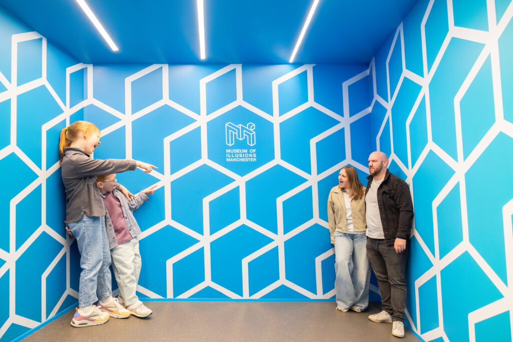 Visitors exploring a blue patterned room at the Museum of Illusions Manchester