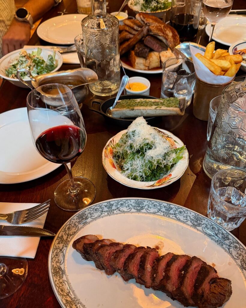 Shared table of steak, salad and wine in a restaurant